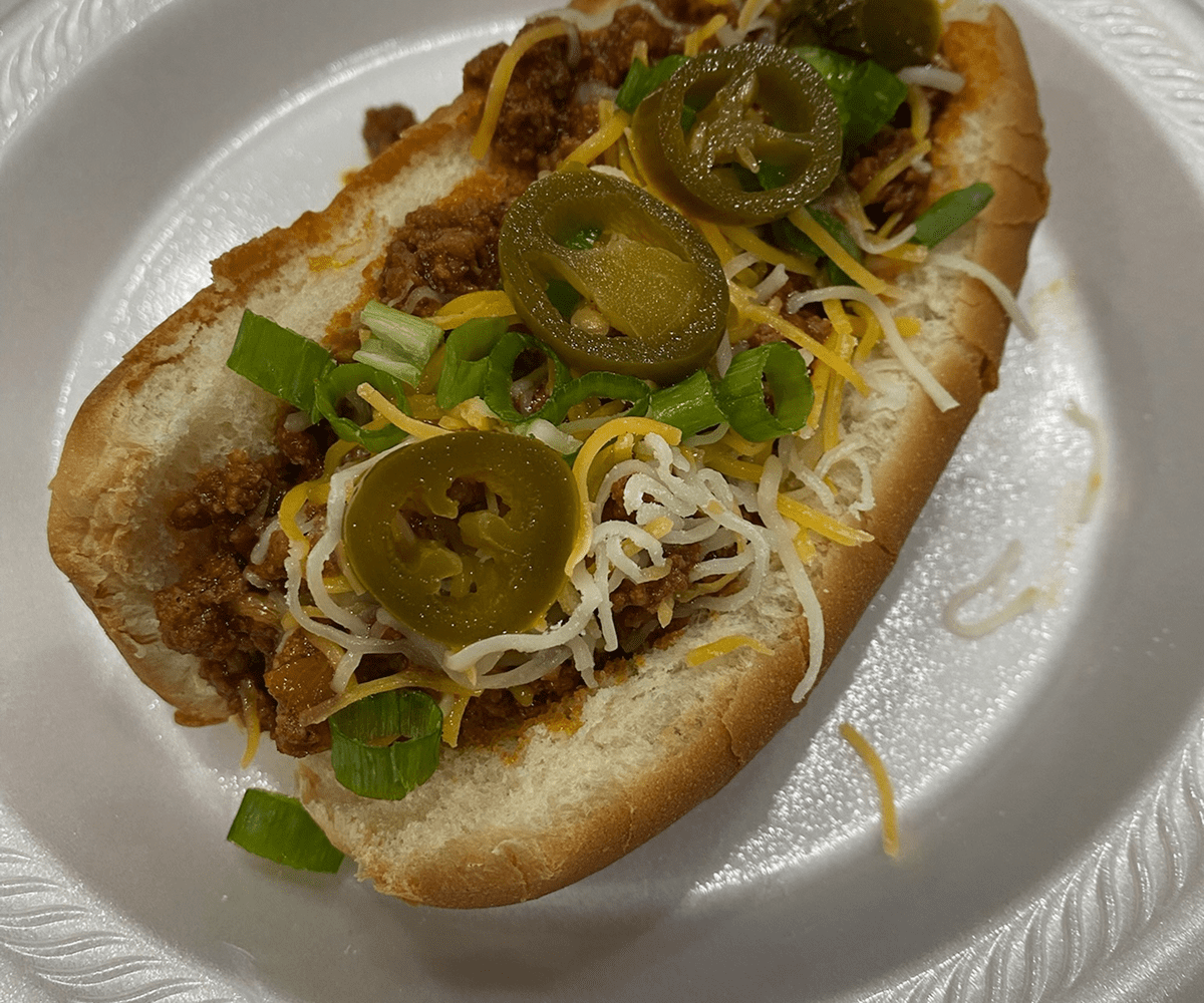 Spicy chili dog on white plate